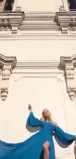 Woman in blue dress against a decorative building backdrop.