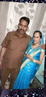 Couple in traditional attire with blue saree and sequin background.