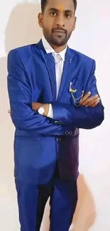 Man in blue suit standing confidently against white background.