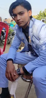 Young man in a blue suit sitting outdoors.