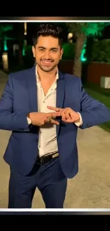 Man in a blue suit standing outdoors at night.