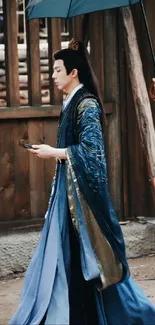 Person in flowing blue traditional attire with umbrella.