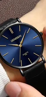 Elegant watch with a blue face on wrist.