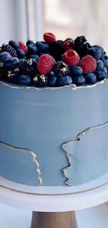 Blue cake with berry toppings on a wooden stand.