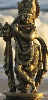 Brass Krishna statue on ocean shore in serene light.