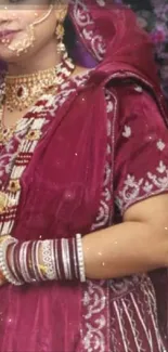 Elegant bridal attire in maroon velvet with gold jewelry.