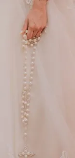 Bridal lace gown with pearl rosary in blush tones.