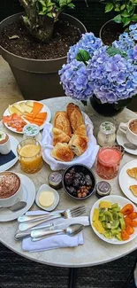 A beautifully set brunch table with pastries, fruit, and vivid hydrangeas.