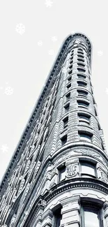 Image of a tall building with snowflakes against a light gray background.