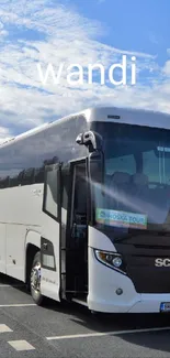 Modern white bus on a scenic road under a blue sky with clouds.