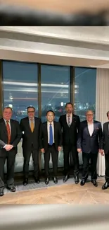 Group of business professionals in suits in front of a city view window.