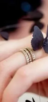 Hand with rings and black butterflies, elegant design.