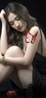 Elegant woman with butterfly tattoo on arm, wearing a black dress.