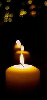 Three candles glowing softly in a dark background with soft bokeh lights.