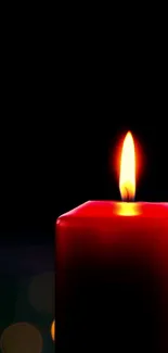 A bright red candle against a dark backdrop, emitting a warm glow.