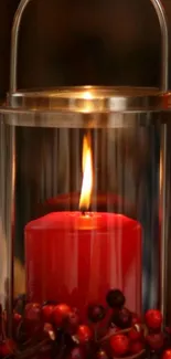 Candle in glass lantern with red berries.