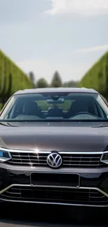 Elegant car on scenic road with lush green background.