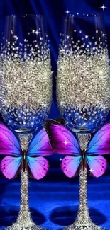 Two sparkling champagne glasses with pink and blue butterflies on a deep blue background.