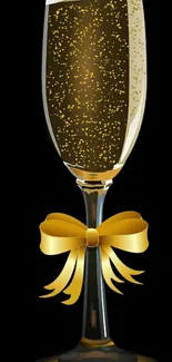 Champagne glass with gold bow on black background.