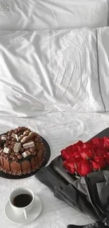 Chocolate cake with red roses on white bedspread.