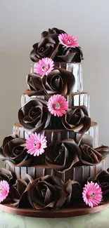 Tall chocolate cake with pink flowers and elegant design.