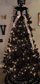 Elegant black Christmas tree with lights and top hat in a living room setting.