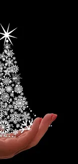 Hand holding a sparkling Christmas tree against a black background.