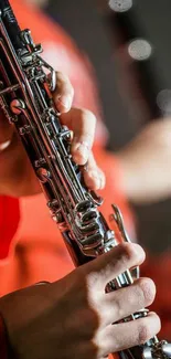 Close-up of a person playing a clarinet in front of a soft red background.