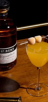 Cocktail and brandy bottle on wooden table.