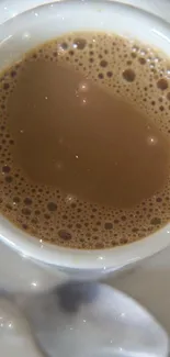 Top-down view of a coffee cup with foam against a red backdrop.