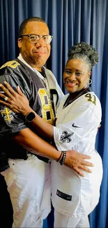 Stylish couple in jerseys with blue curtain backdrop.