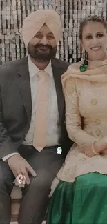 A couple in elegant traditional attire seated together, exuding cultural charm.