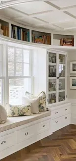 Elegant reading nook with white shelves and window seat.