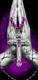 Hands holding a silver cross with a purple halo and beads on a dark background.