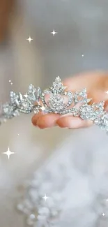 Delicate silver crown held in a hand.