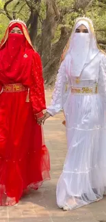 Two women in red and white traditional dresses outdoors.