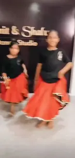 Elegant dancers in red skirts at a dance studio.