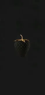 Sleek black strawberry with gold highlights on dark wallpaper.