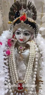 An intricately adorned deity statue with floral garlands and beads.