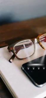 Minimalist office desk with phone and glasses on notepad.