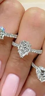 Three diamond rings on hand with soft pink nails.