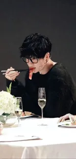 Dark-haired person dining elegantly with a stylish setup.