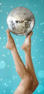 Elegant disco ball balanced on feet against a light blue background.