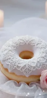 Elegant donut with lace icing surrounded by candles and a rose.