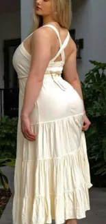 Woman in cream dress standing outdoors.