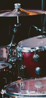 Close-up of a maroon drum set on stage with microphones.