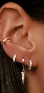 Close-up of ear with elegant gold earrings and piercings.