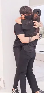 Elegant couple in black clothes embracing in sunlight.