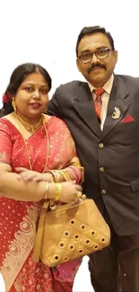 Elegant couple in traditional ethnic attire on a neutral background.