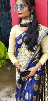 Woman in blue and gold saree with modern accessories.